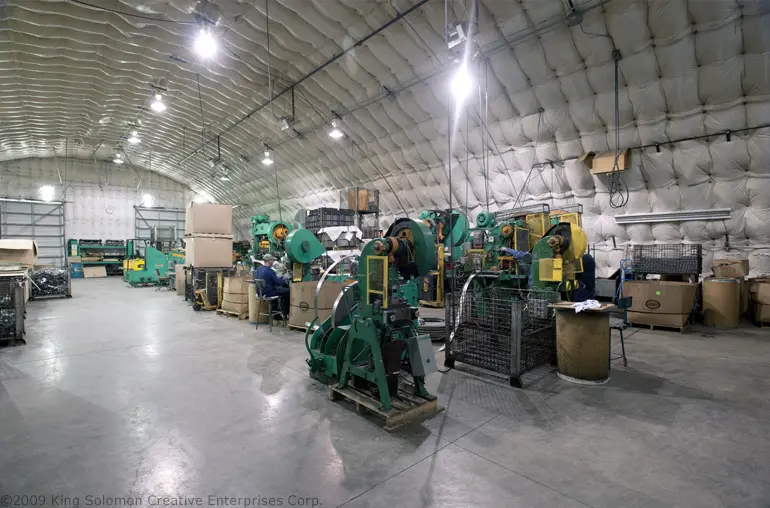 A worker inside a steel industrial building operating machinery
